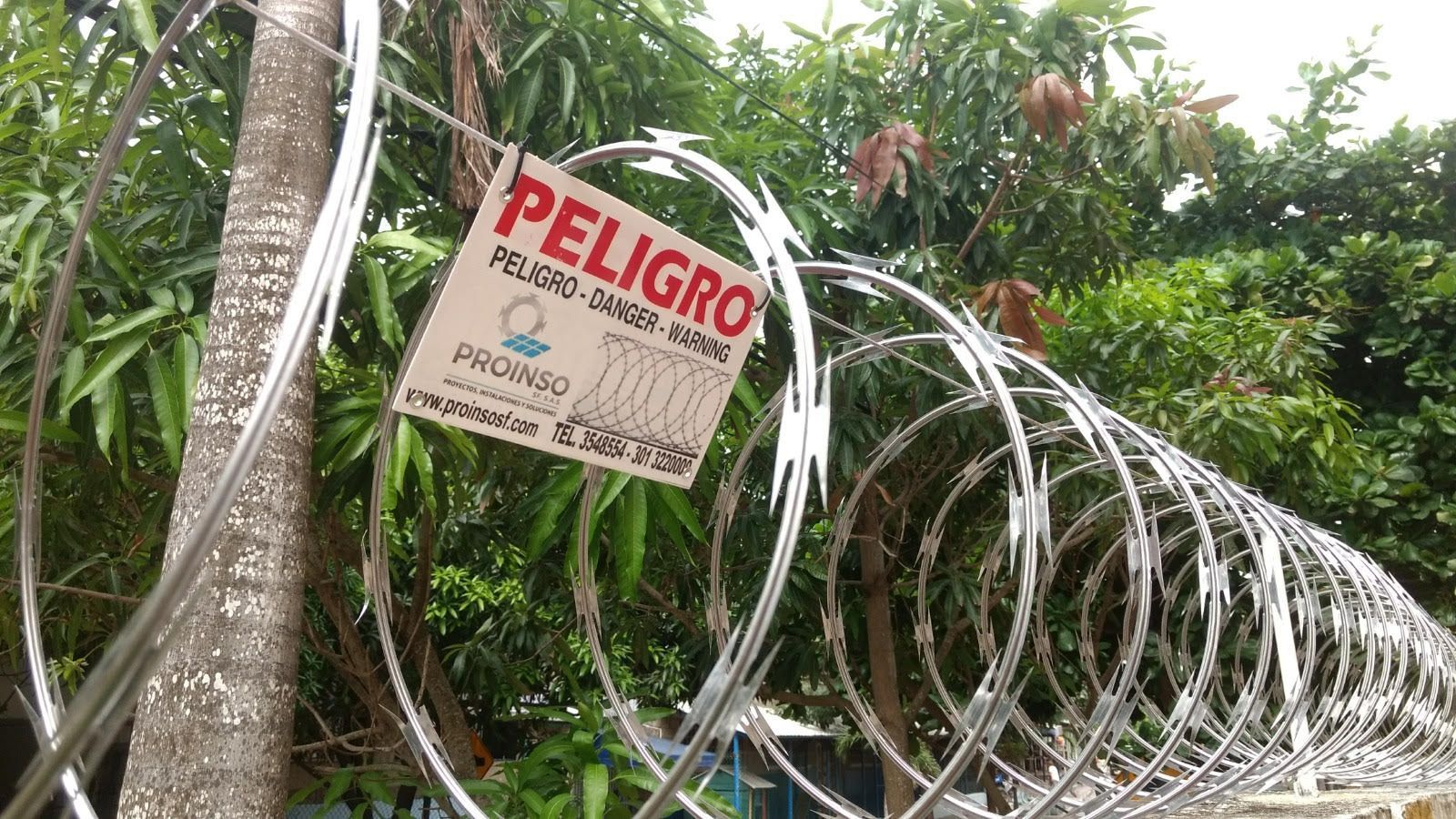 Bobinas de alambre de púas sobre una puerta y un muro metálico