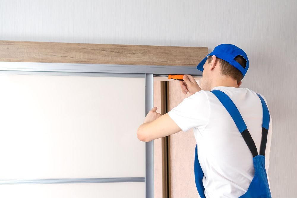 A Man Is Measuring A Sliding Door With A Tape Measure — Dachboe Your Handyman in Ingham, QLD