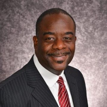 A man in a suit and tie is smiling for the camera.