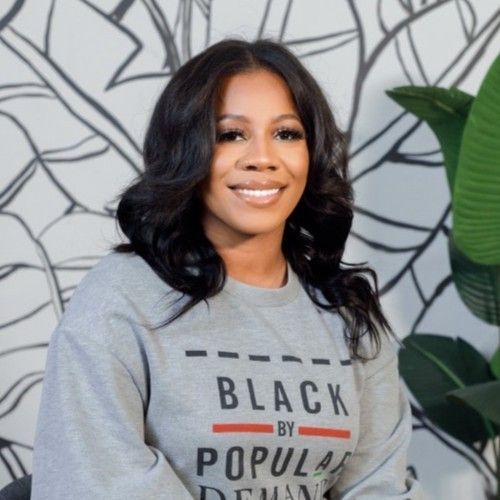 A woman wearing a grey sweatshirt that says black by popular demand