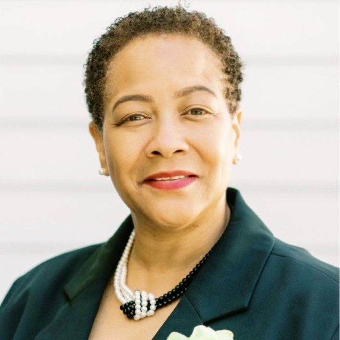 A woman wearing a pearl necklace and a black jacket