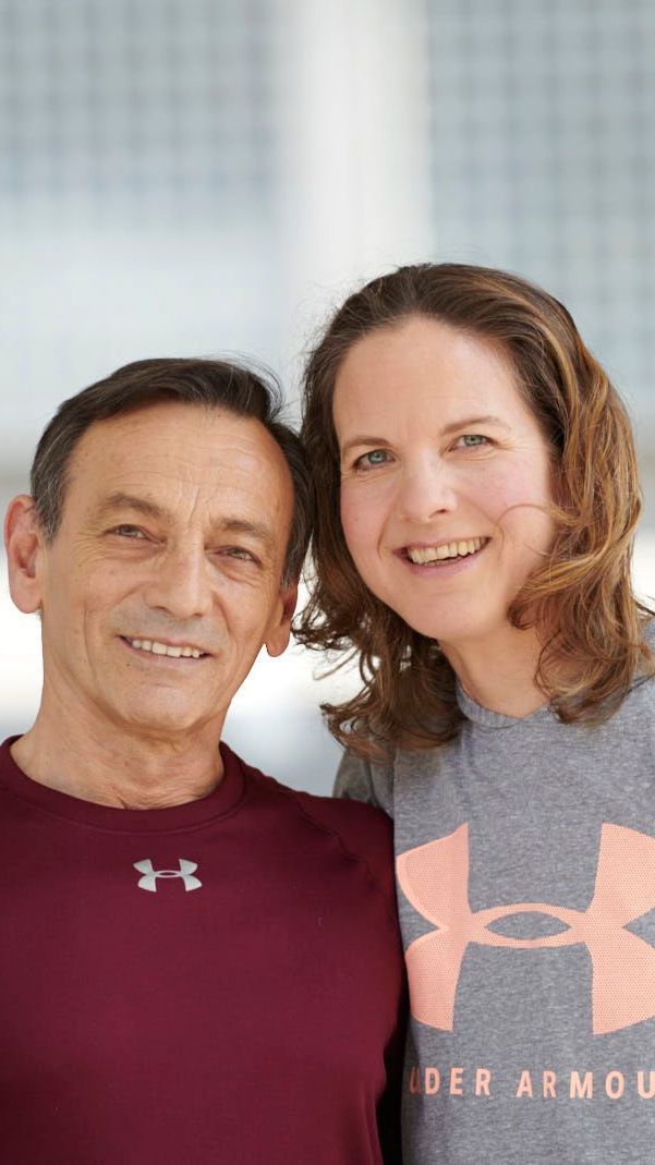 Ein lächelndes Paar posierte eng beieinander. Der Mann trug ein weinrotes Hemd, die Frau ein graues Sportshirt.