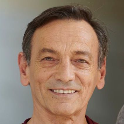 Lächelnder Mann mit kurzen dunklen Haaren im Freien.