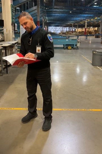 Warehouse worker reading a red clipboard in a large industrial loading bay