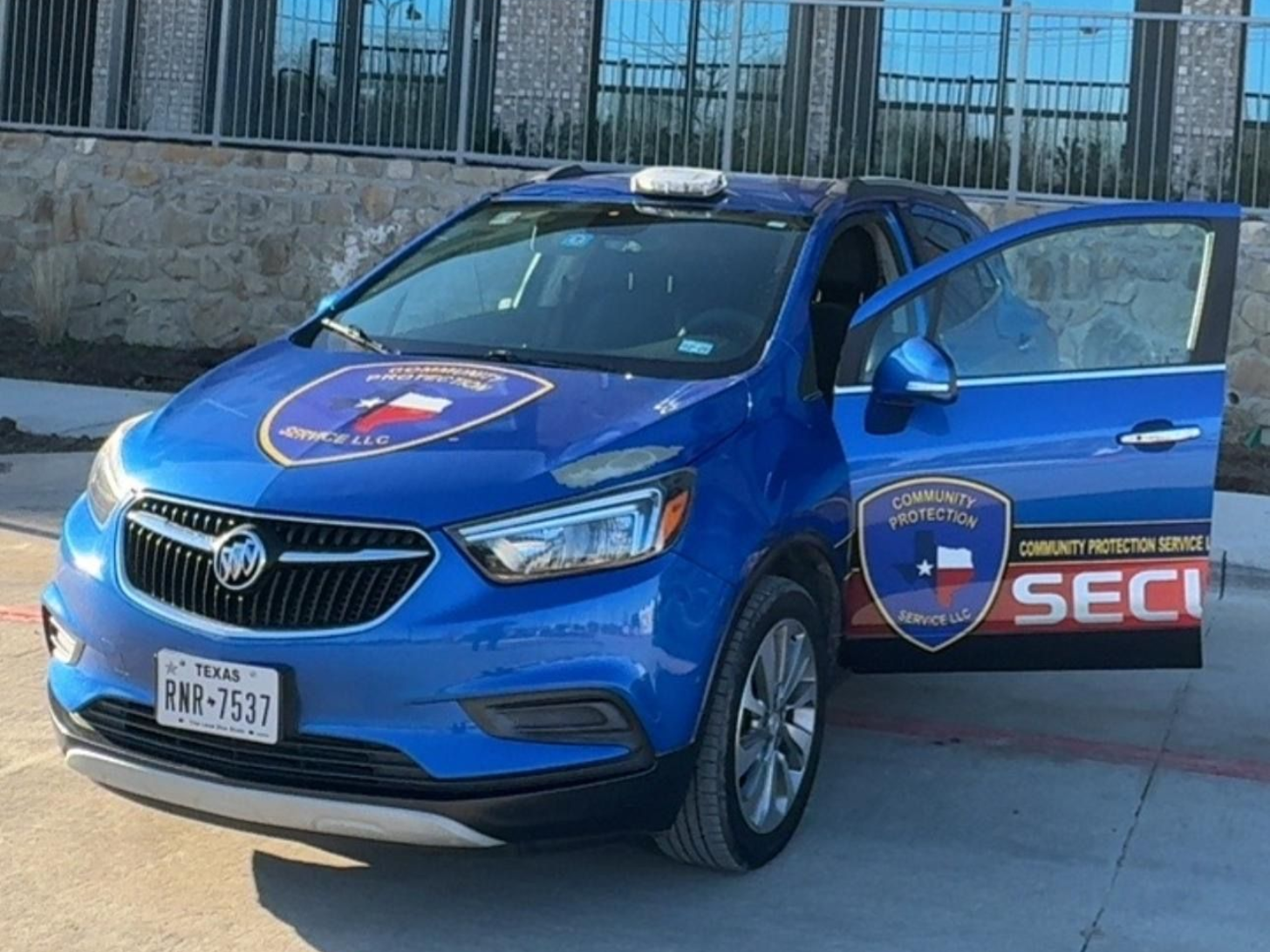 Blue security SUV parked with driver door open, security logos visible on hood and side.