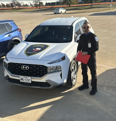 Person standing beside a white Hyundai SUV in a parking lot, holding a red bag.