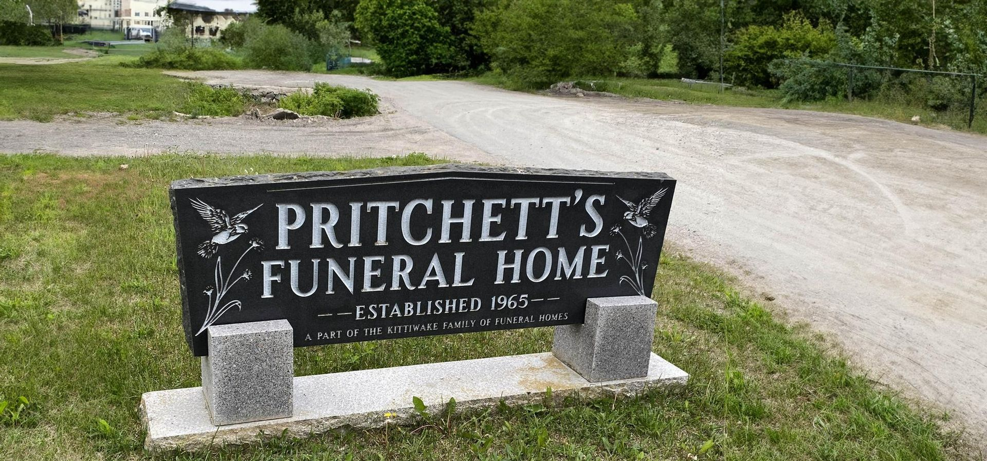 Pritchett’s Funeral Home sign on a stone base beside a gravel driveway