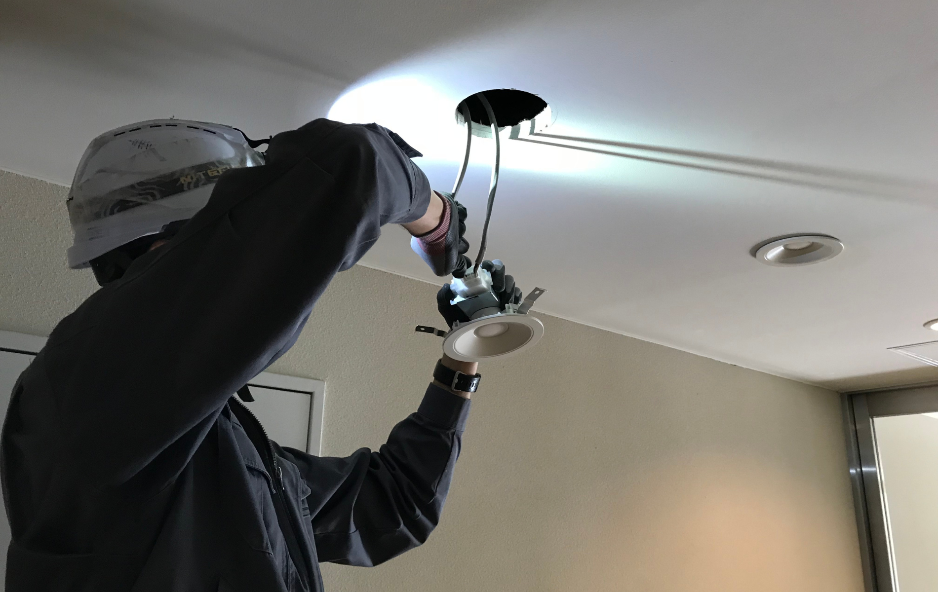 Electrician installing a recessed light fixture in a ceiling.