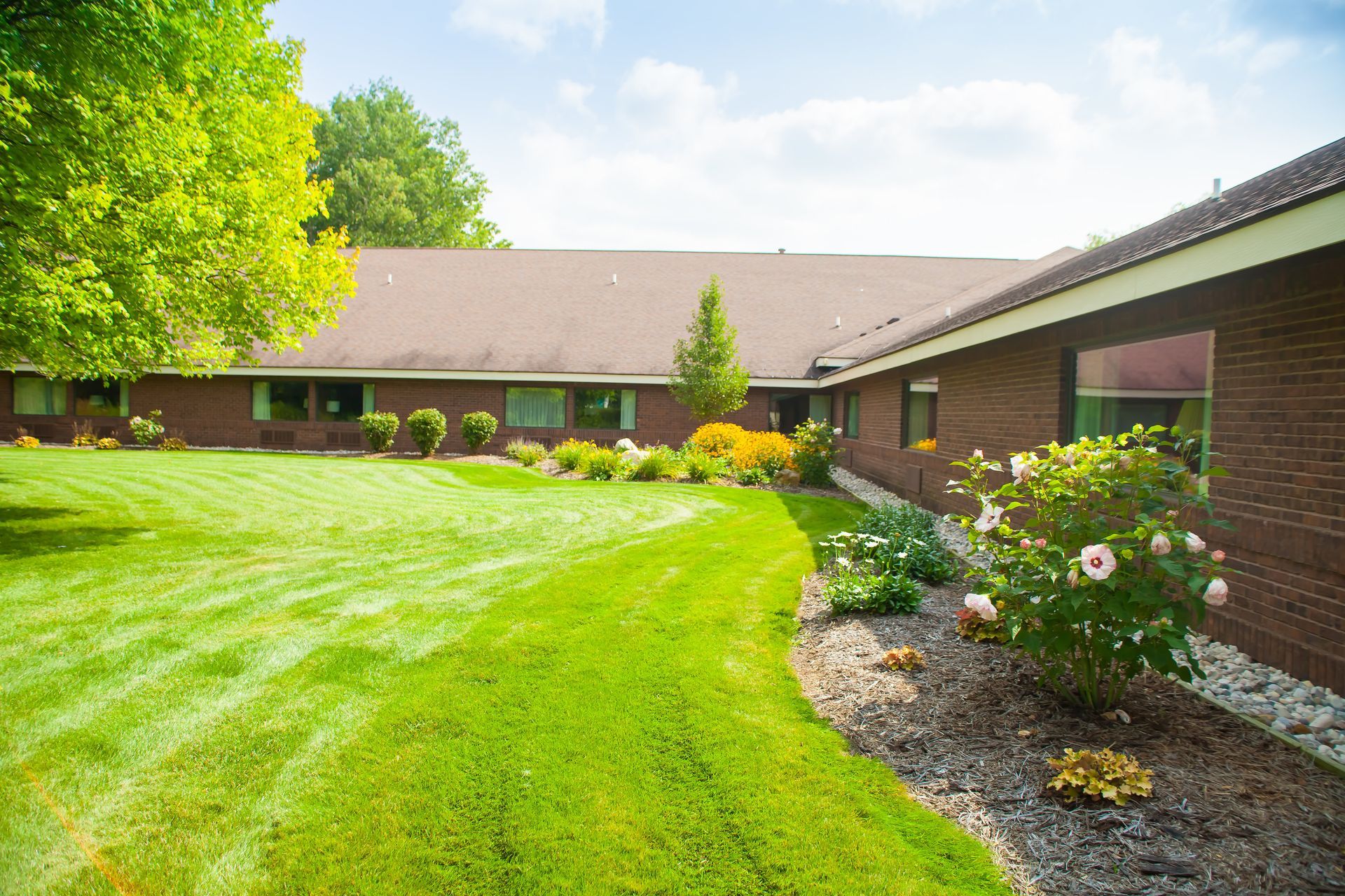 A large brick house with a lush green lawn in front of it.