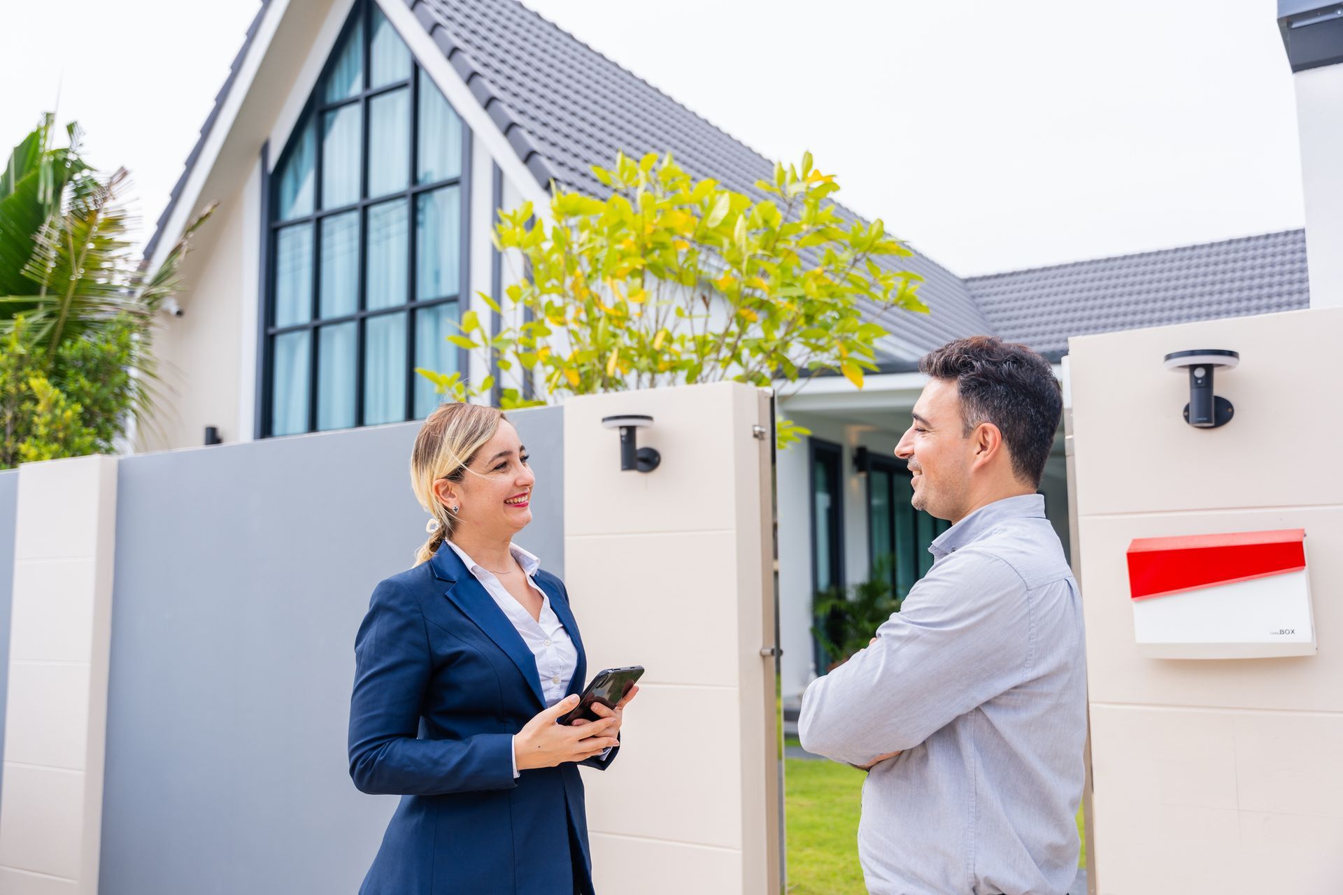 A woman is talking to a man in front of a house.