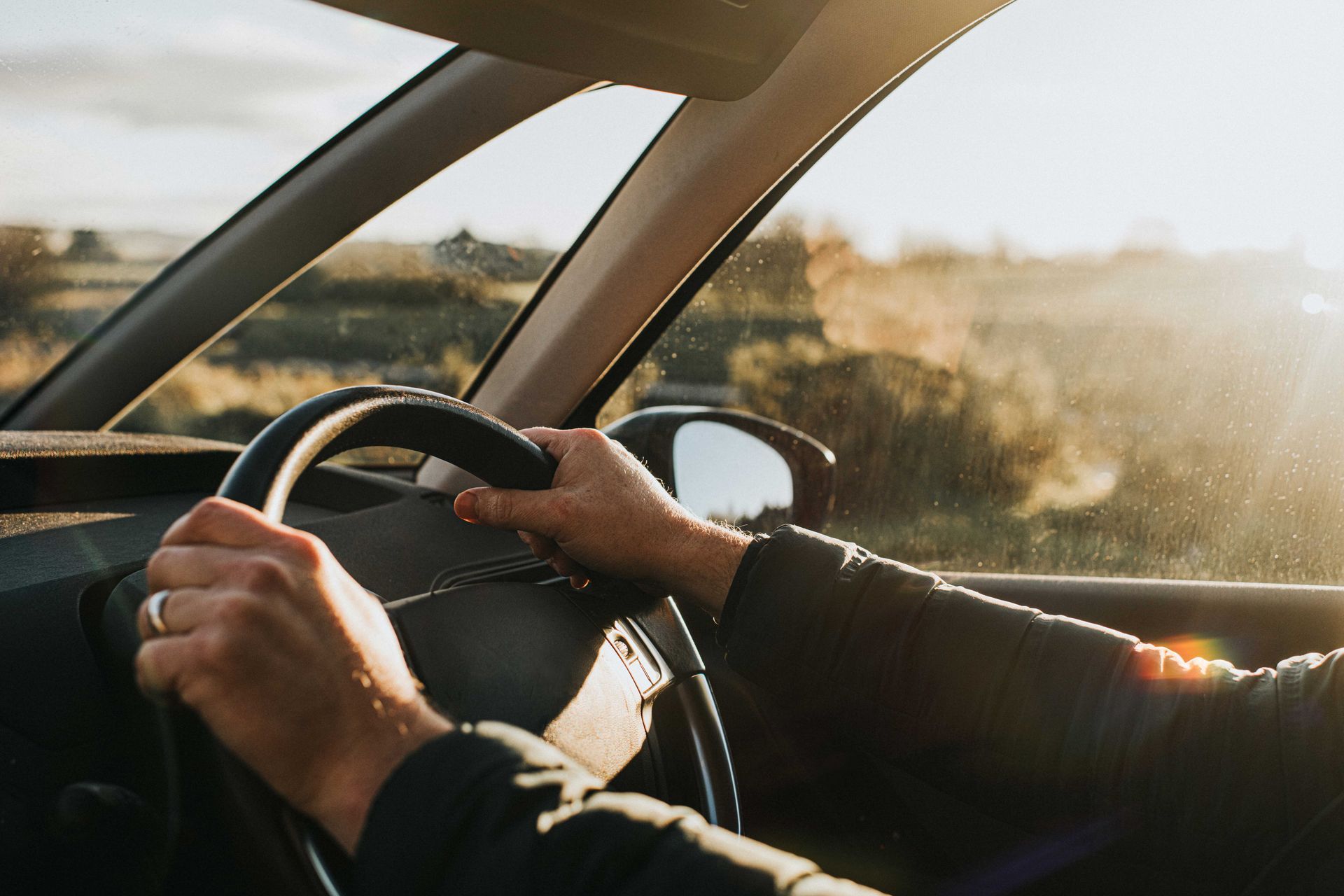 A person is driving a car with their hands on the steering wheel.