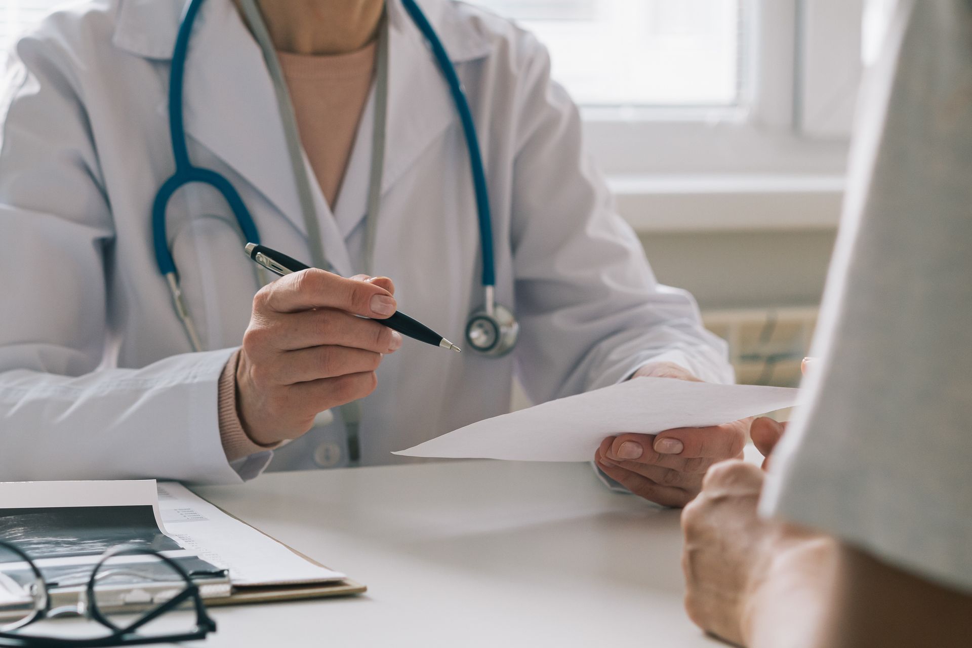 A doctor is talking to a patient while holding a piece of paper.