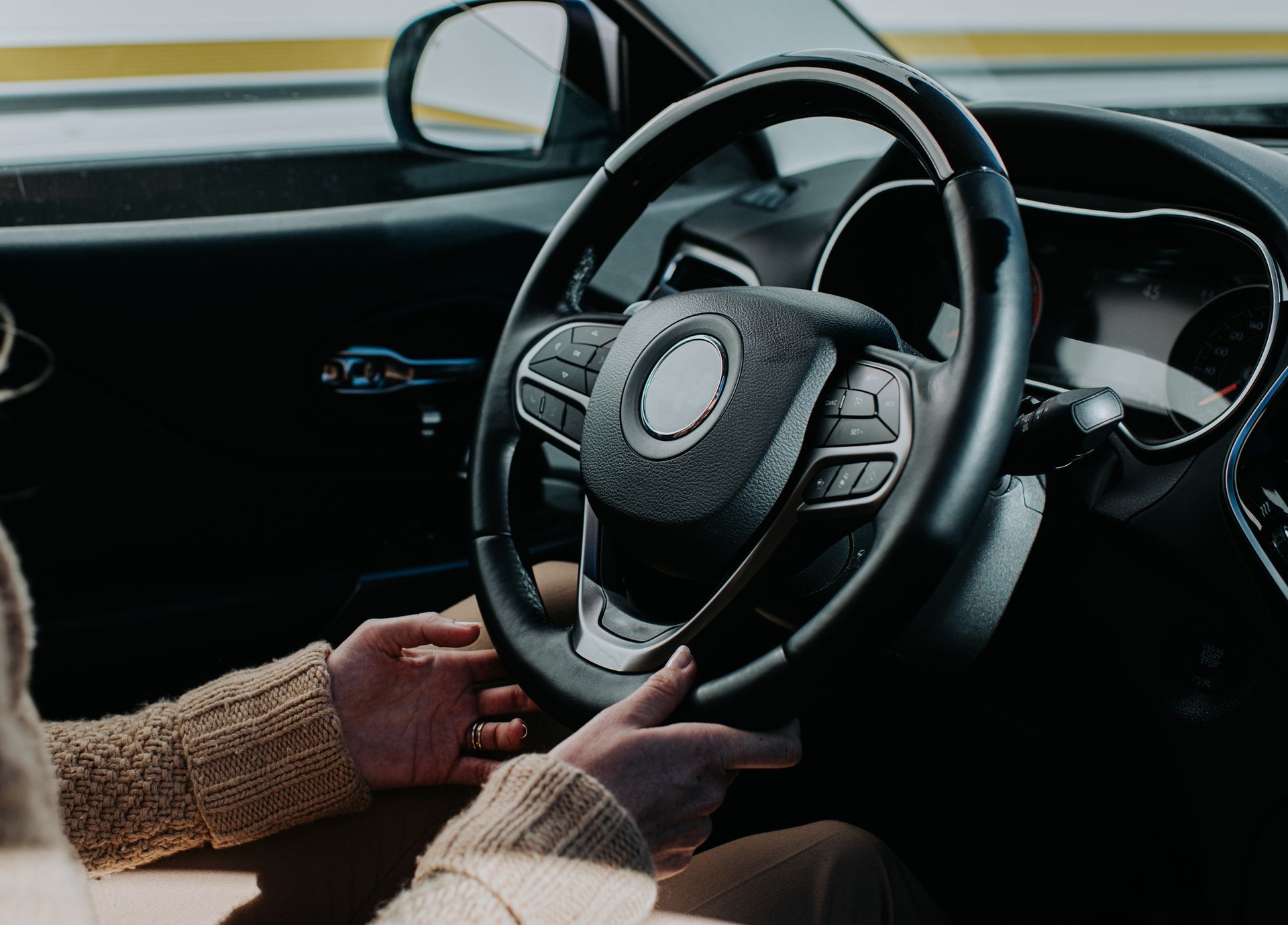 A person is holding the steering wheel of a car.