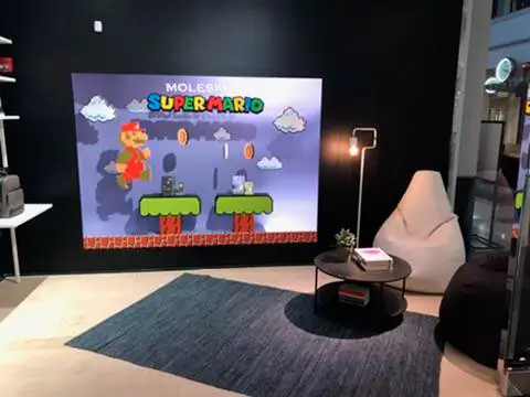 A living room with a super mario game on the wall.