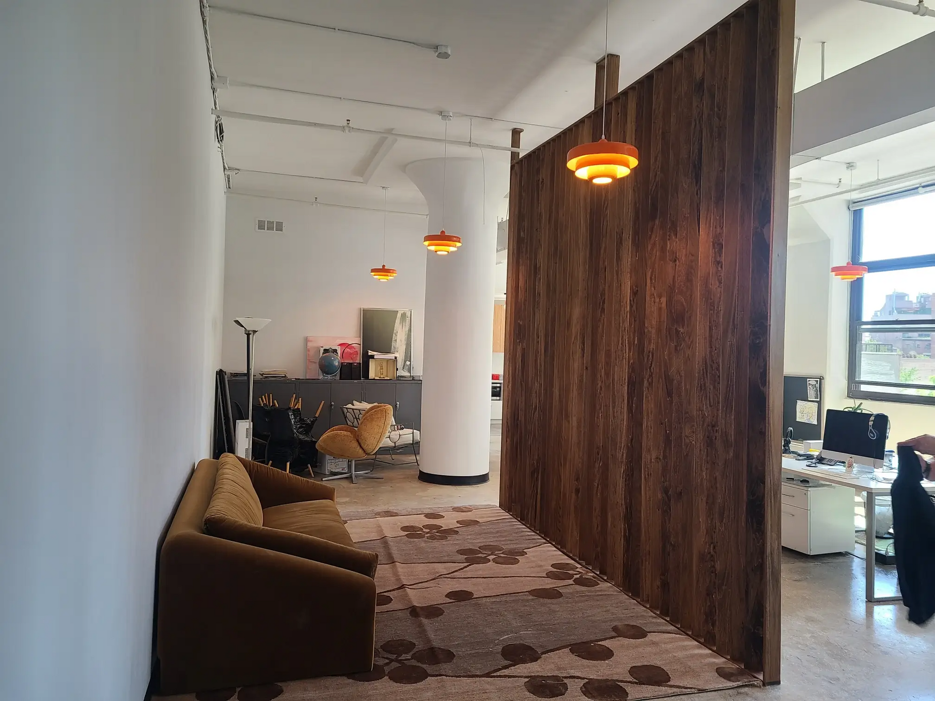 A living room with a couch and chairs and a wooden wall