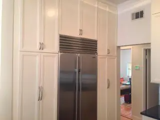 A kitchen with white cabinets and a stainless steel refrigerator.