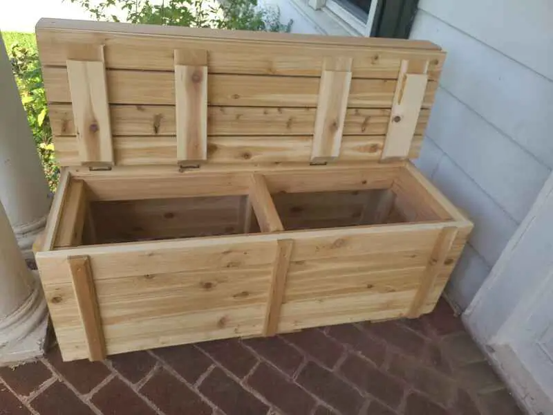A wooden box is sitting on a porch with the lid open