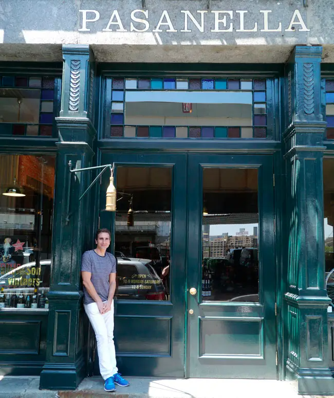 A man stands in front of a restaurant called pasanella