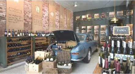 A car is parked in a wine store with the trunk open