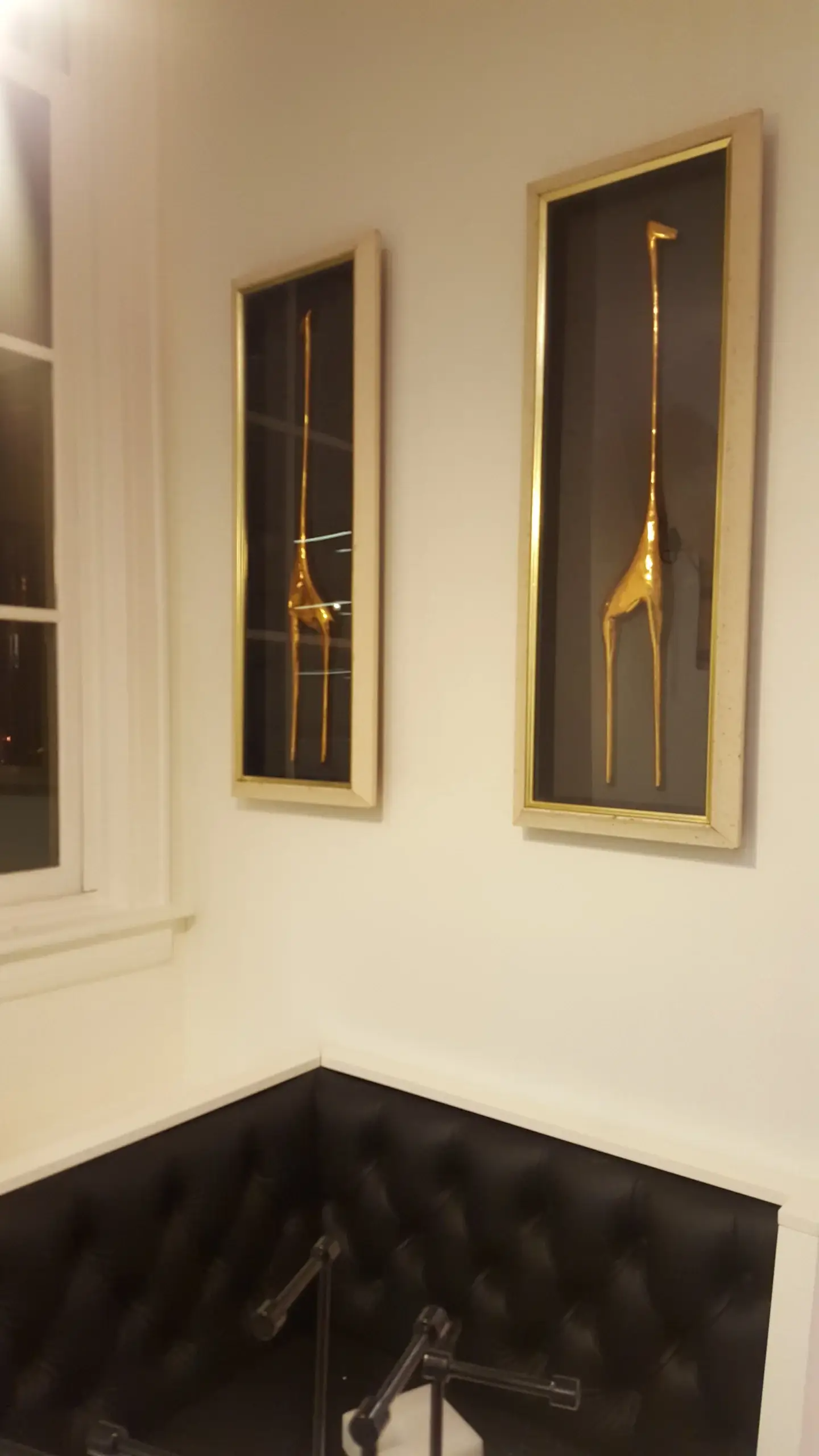 A corner of a room with two framed giraffes on the wall
