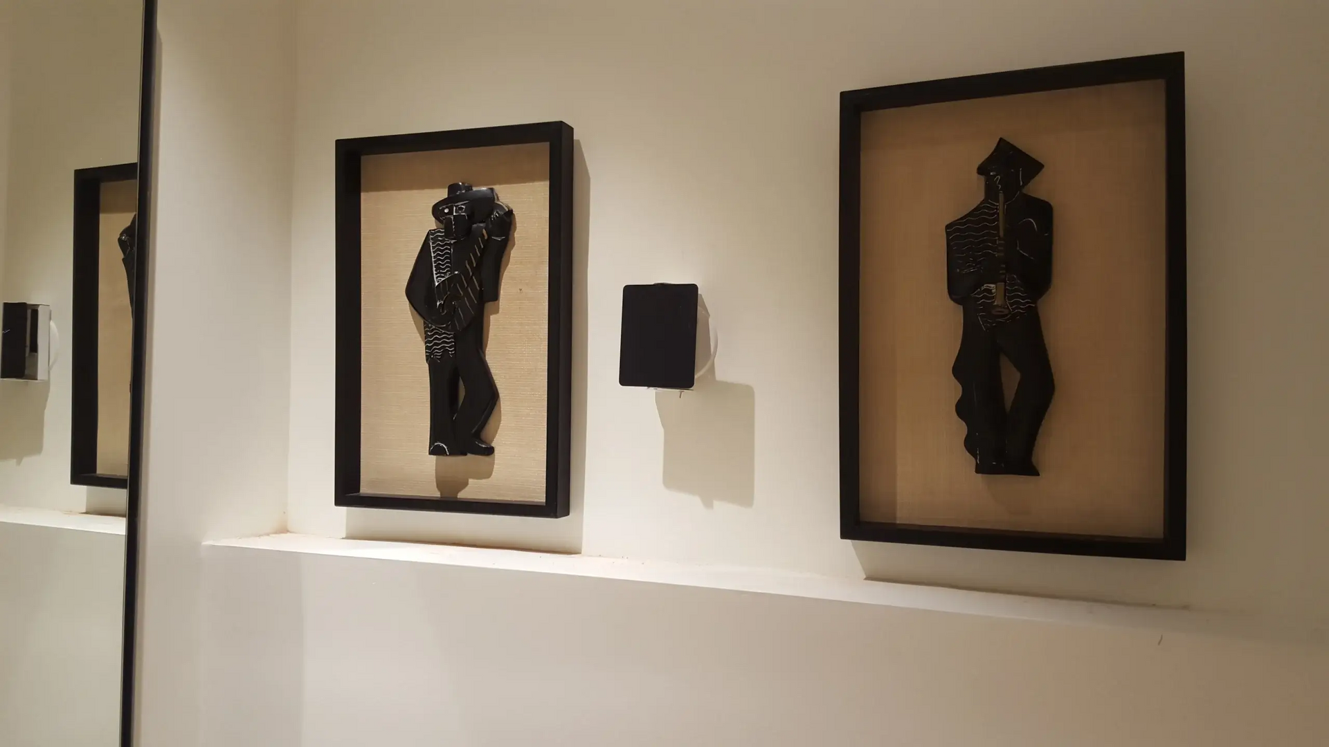 A row of black paintings on a white wall