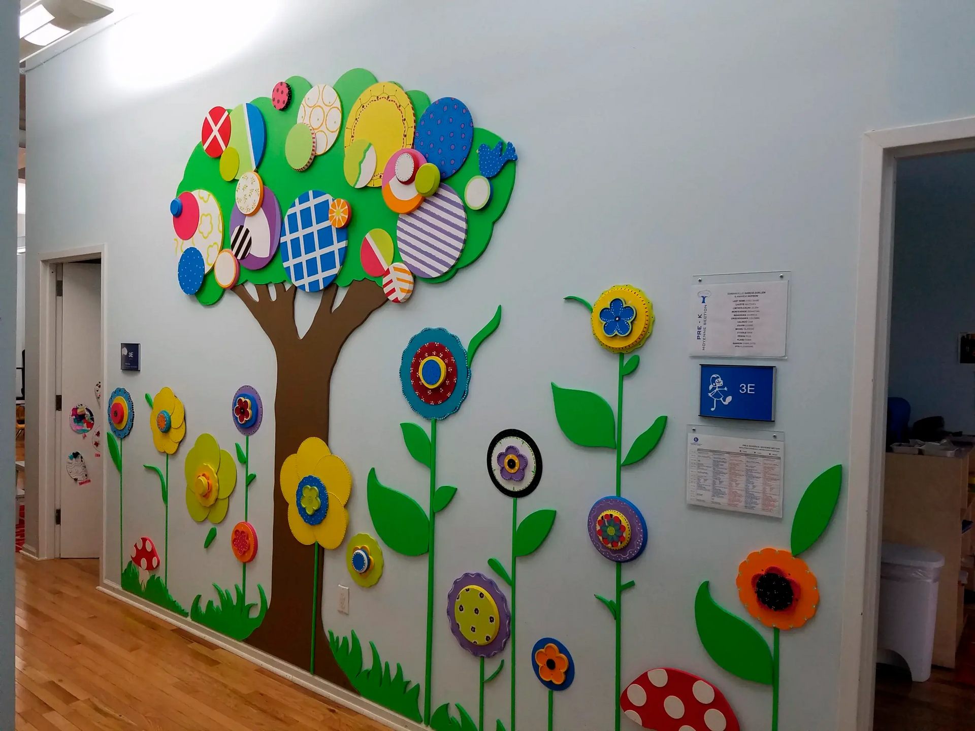 A hallway with a tree and flowers on the wall
