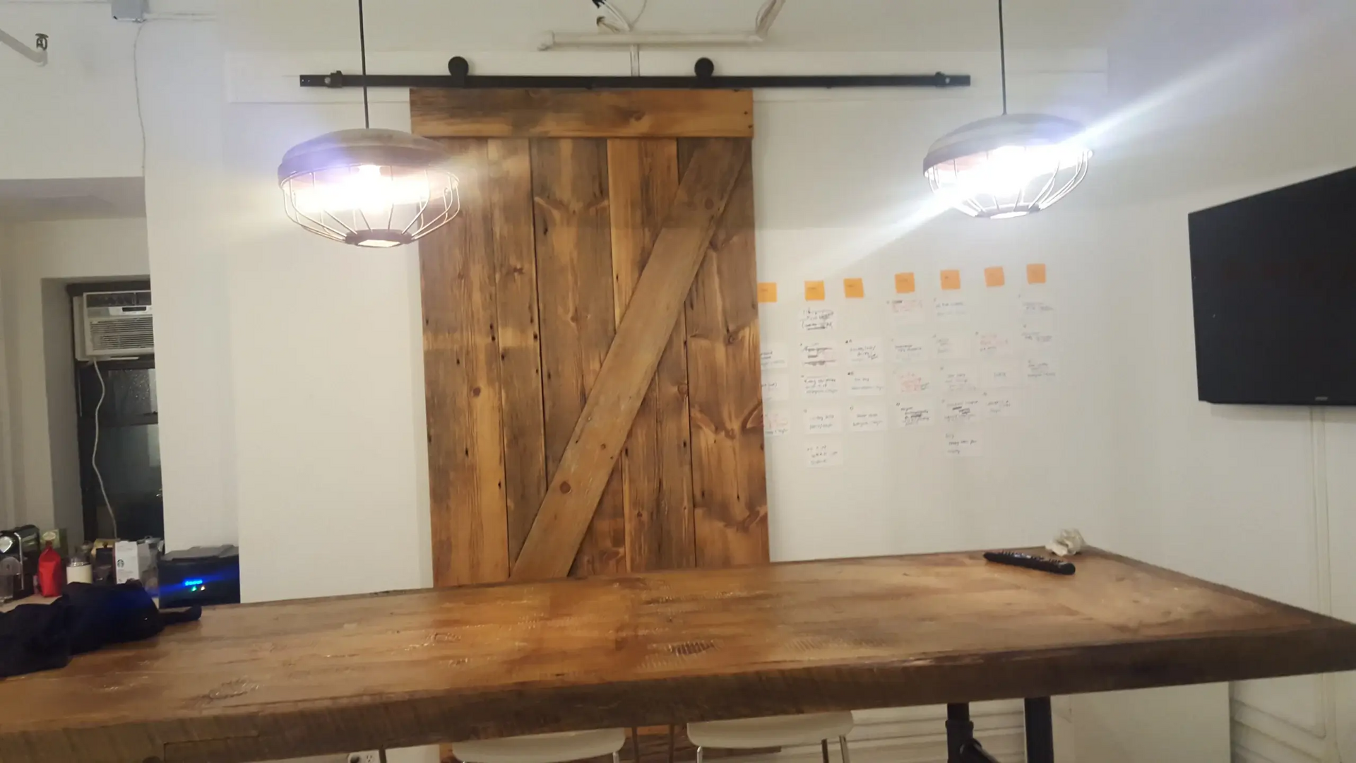 A conference room with a wooden table and a sliding barn door.