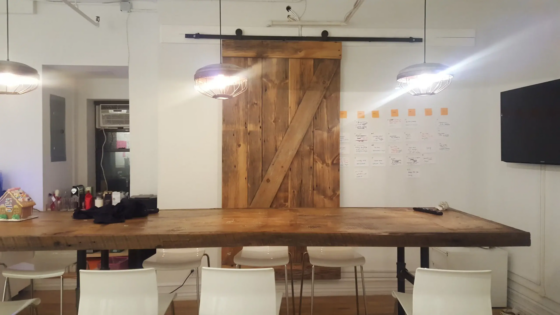 A conference room with a wooden table and chairs and a sliding barn door.