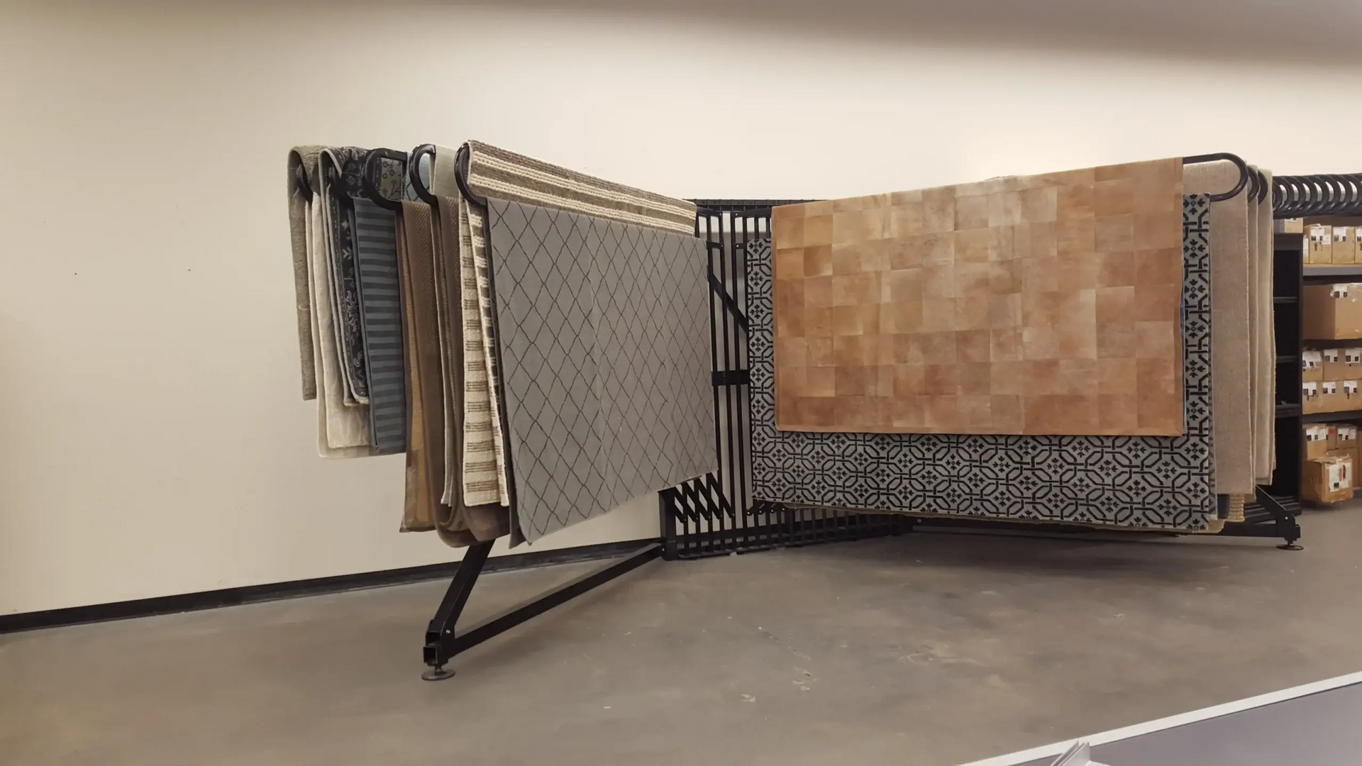 A bunch of rugs are hanging on a rack in a room.