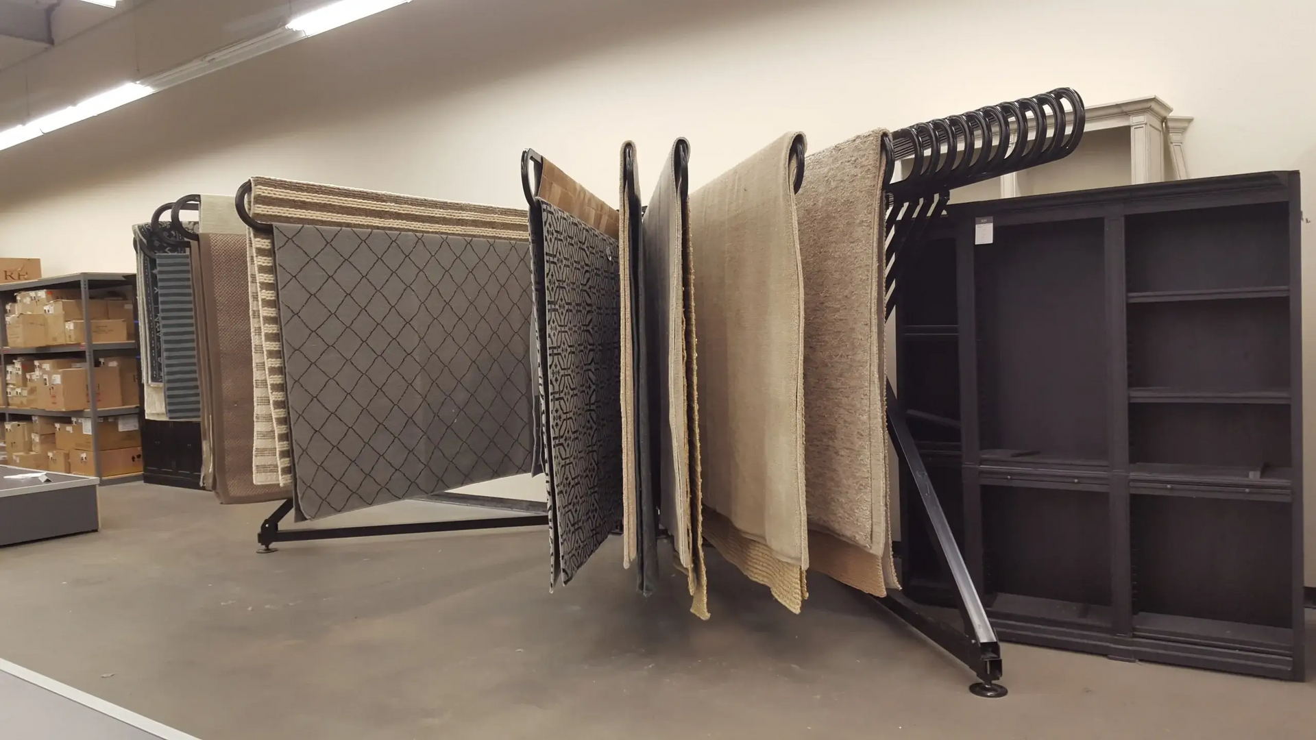 A bunch of rugs are hanging on racks in a room.