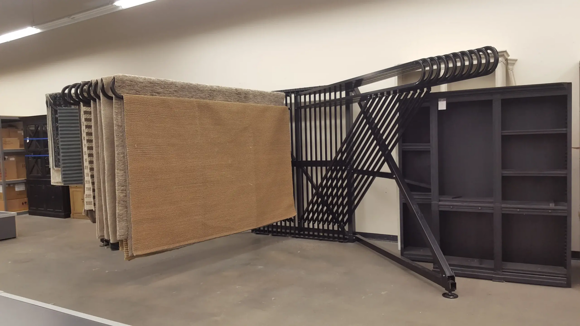 A bunch of rugs are hanging on a rack in a room.
