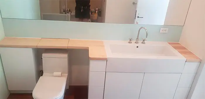 A bathroom with a toilet , sink and mirror.