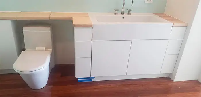 A bathroom with a toilet , sink and cabinets.