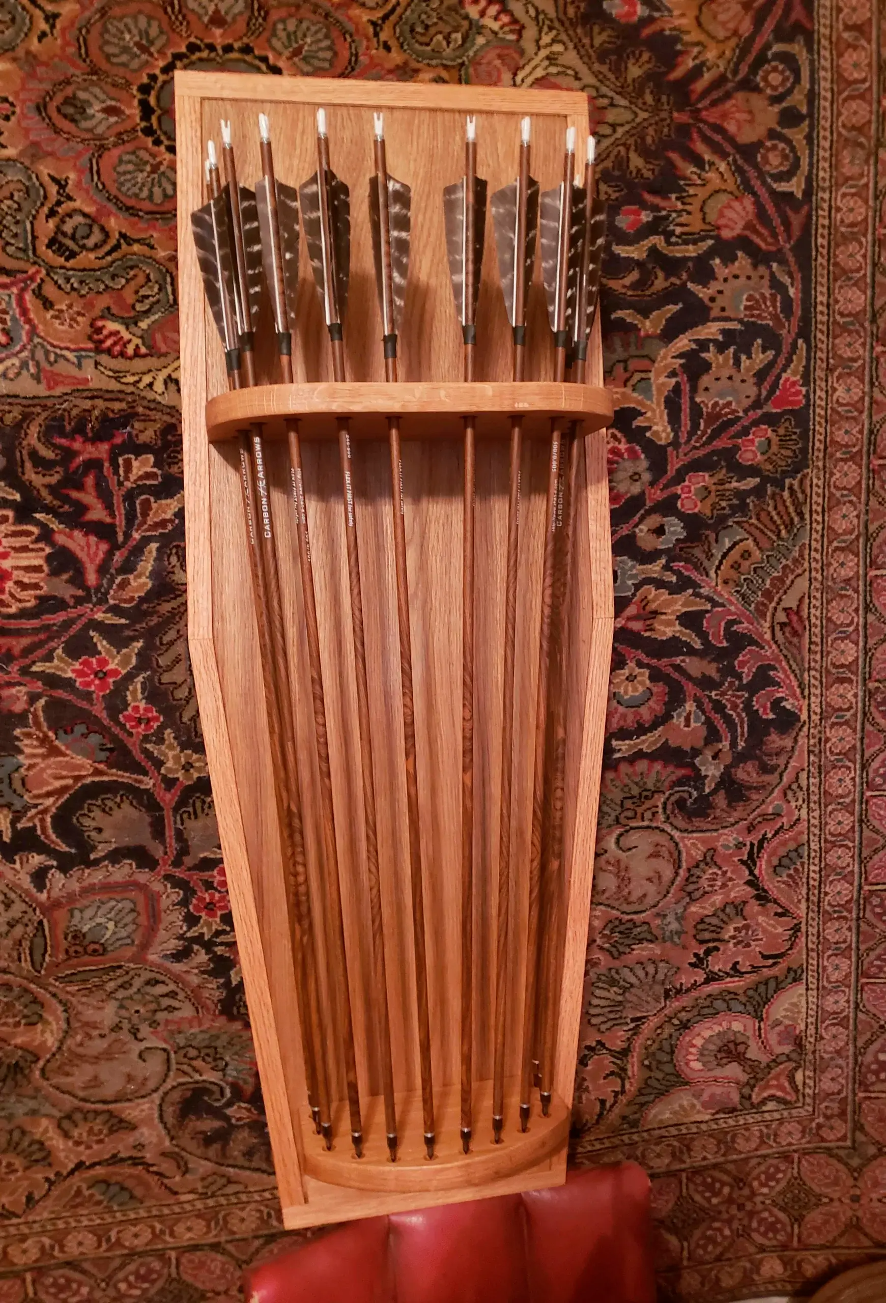 A bunch of arrows are hanging on a wooden shelf.