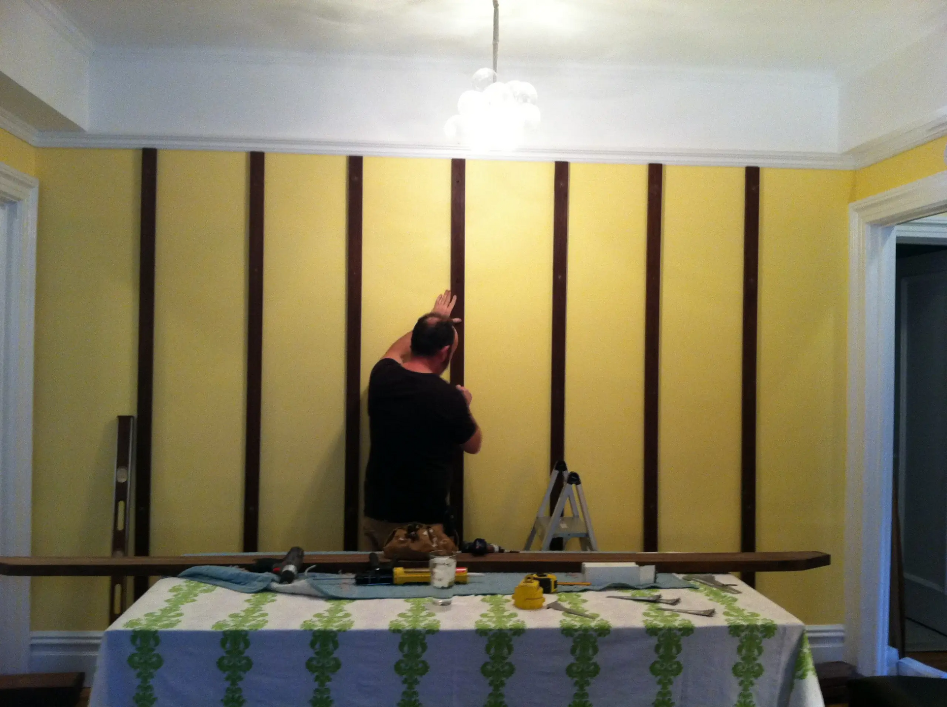 A man is working on a wall behind a table