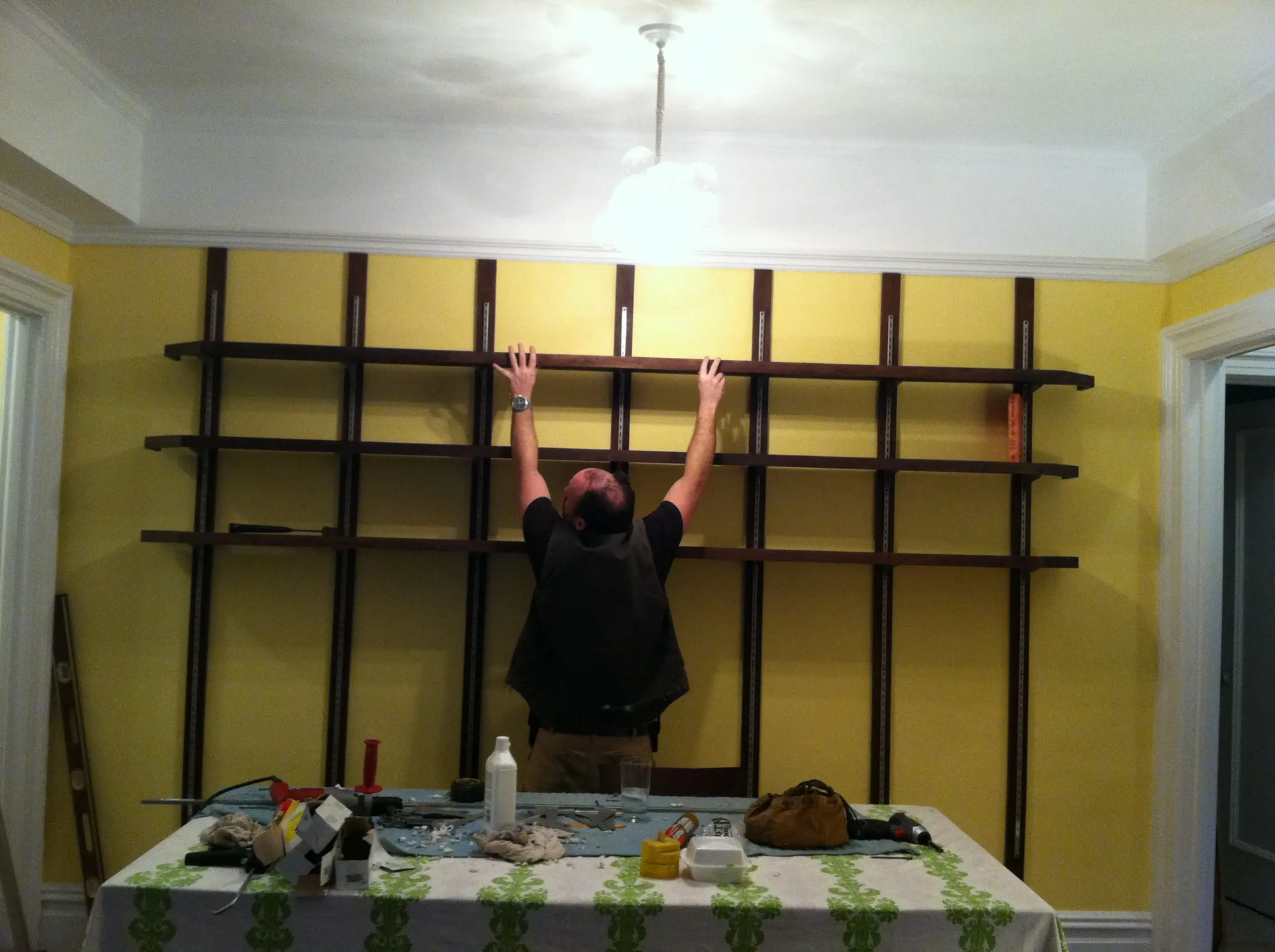 A man is hanging shelves on a wall in a room