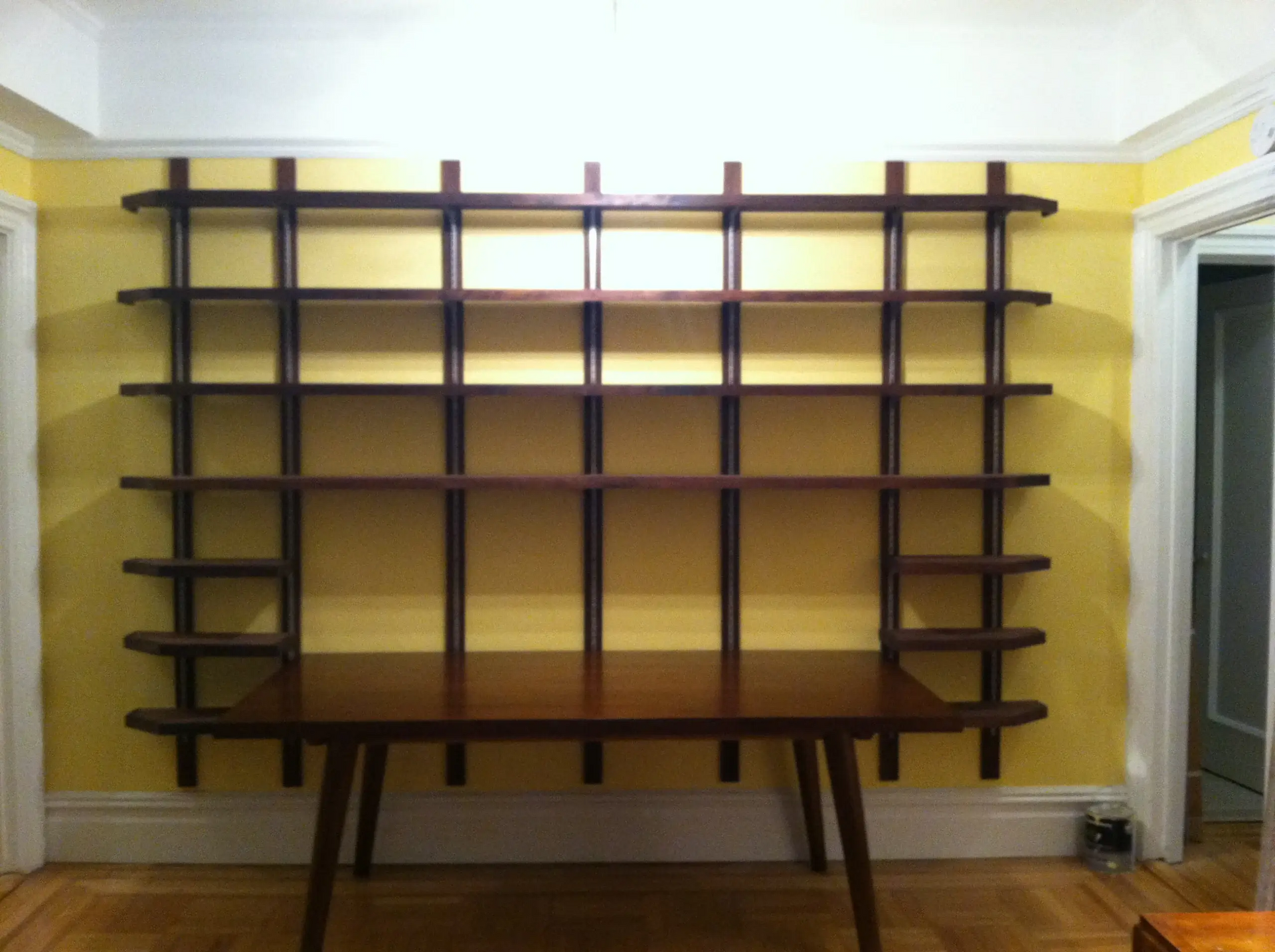 A wooden table in front of a wall with shelves