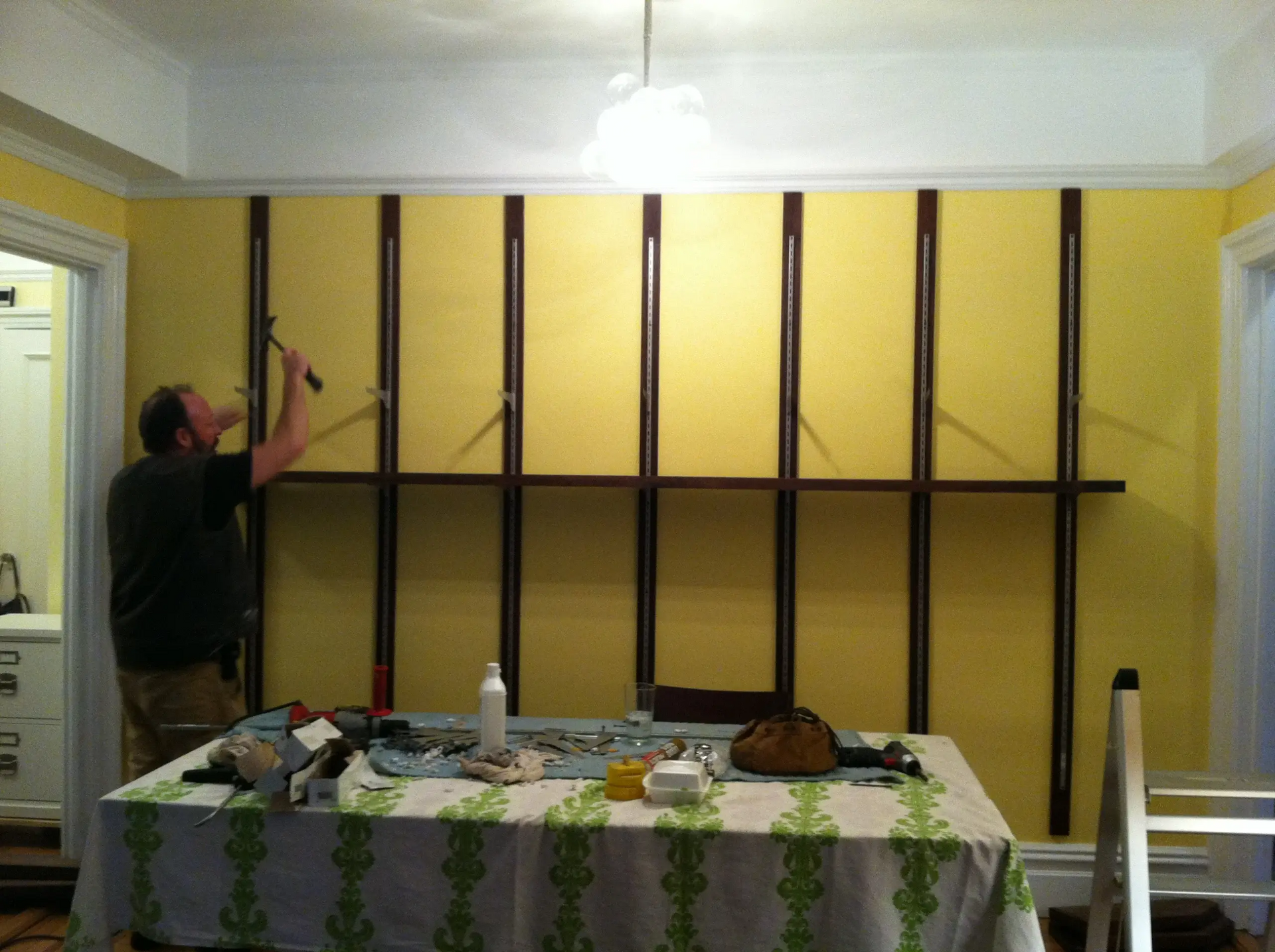 A man is working on a wall behind a table