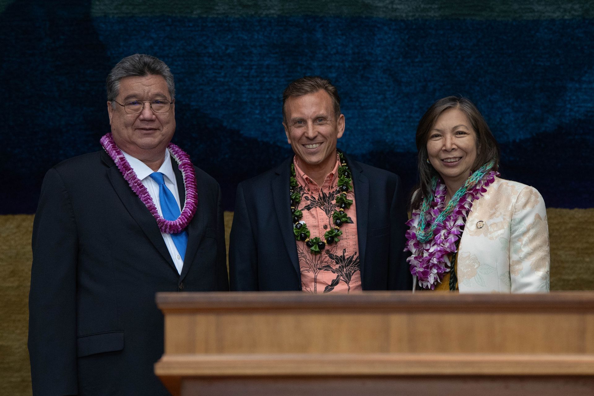 Three people are standing next to each other in front of a podium.