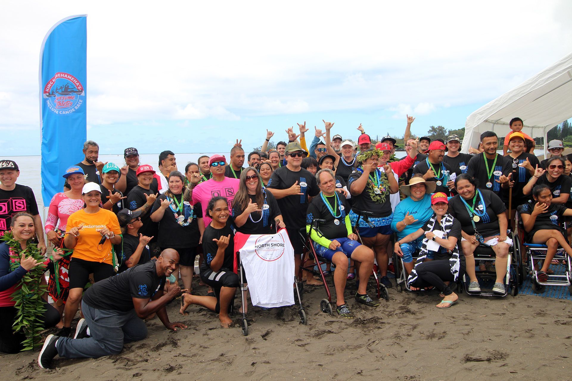 A group of people are posing for a picture on the beach.