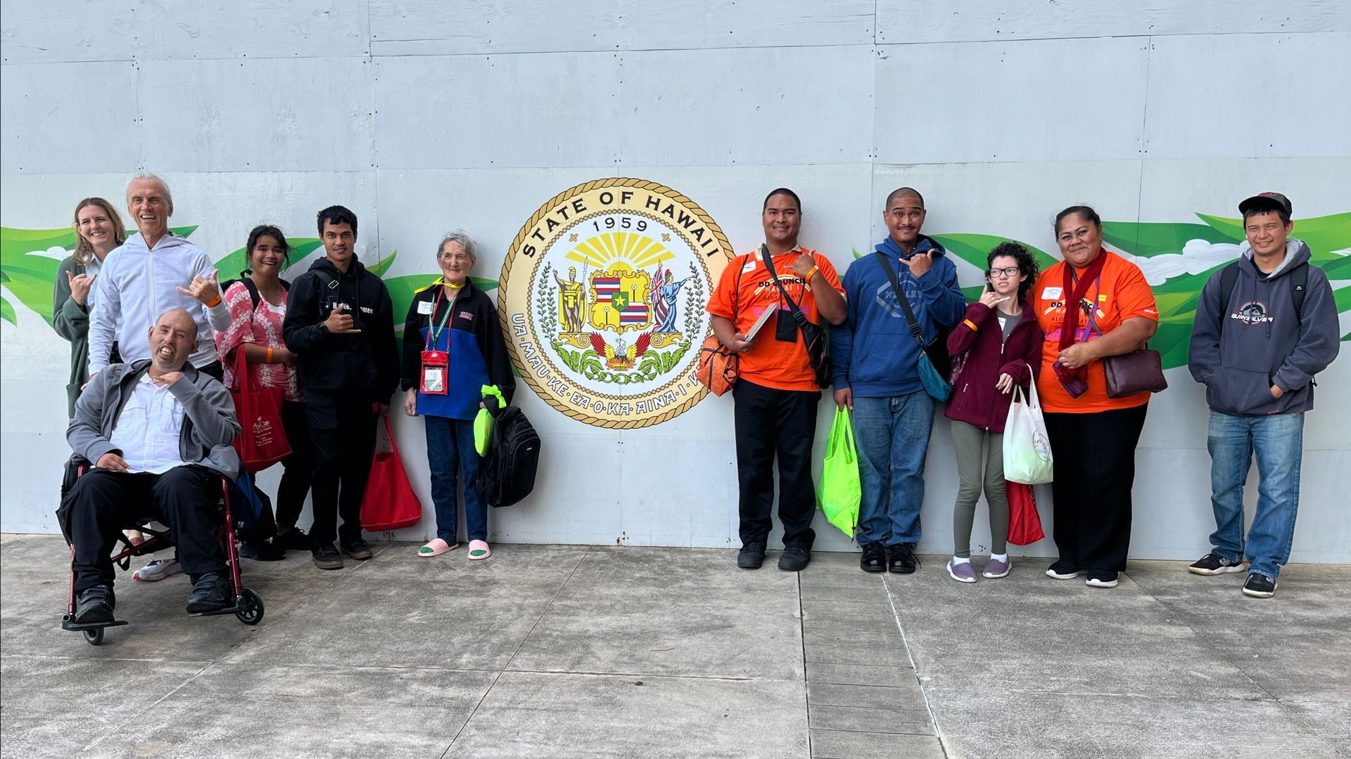 Group of people posing outdoors in front of a city seal, some holding flags and wearing jackets