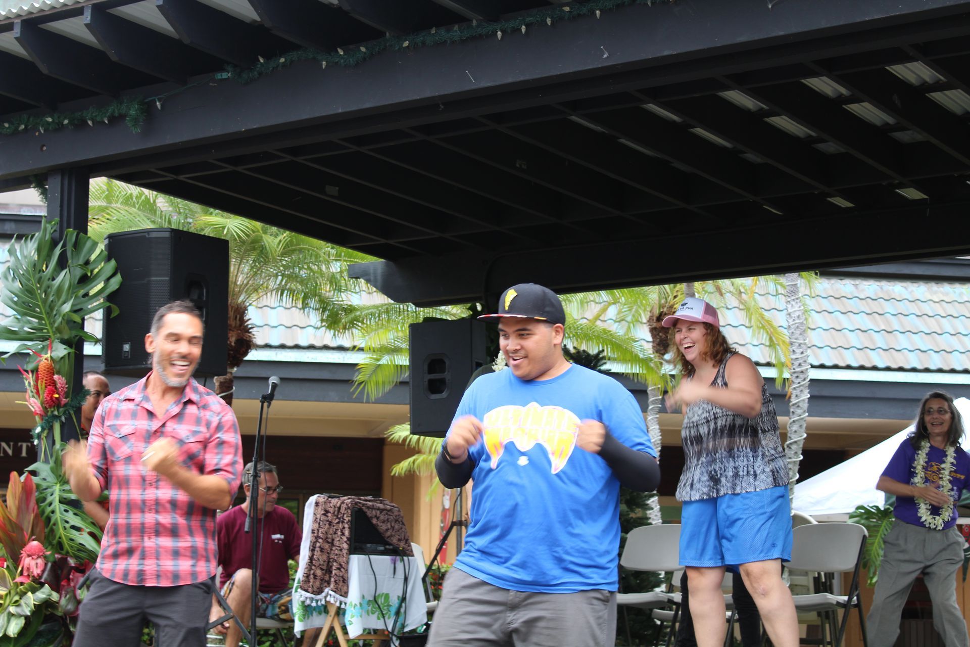 A group of people are dancing on a stage under a canopy.