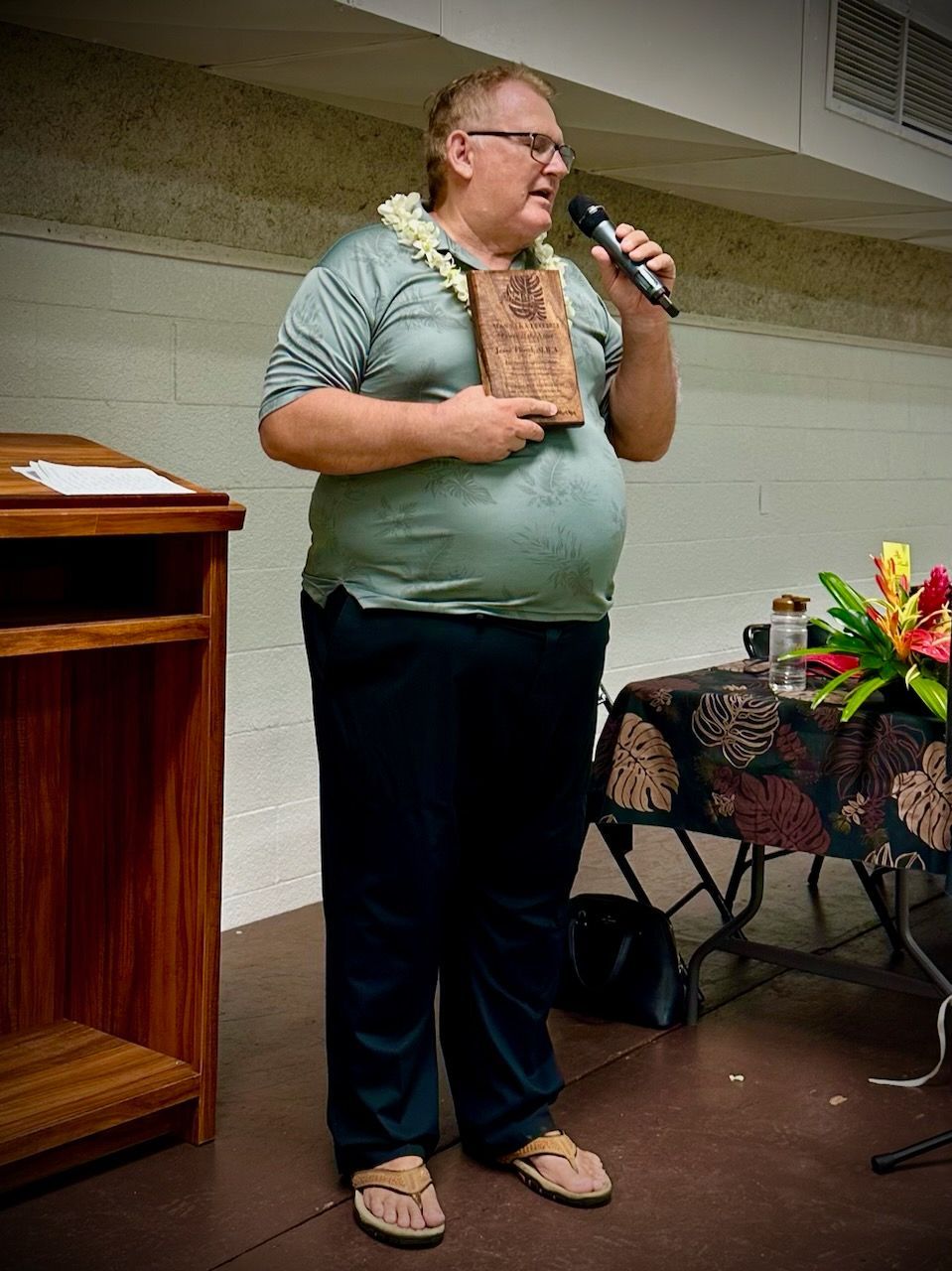 A man is standing on a stage holding a microphone and a book.