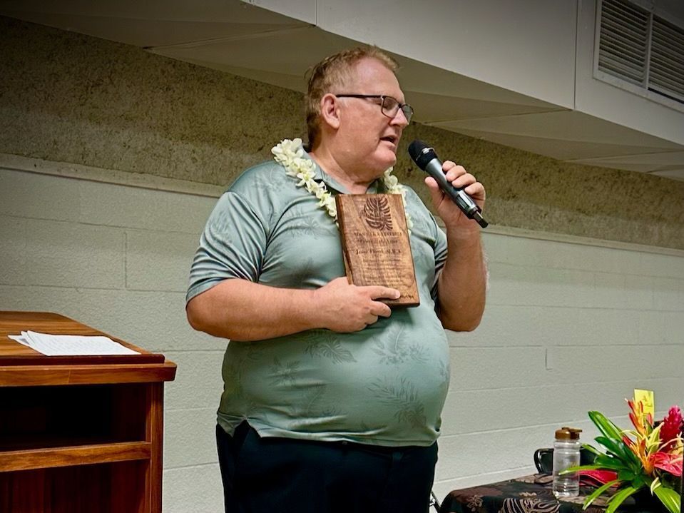A man is holding a plaque and speaking into a microphone.