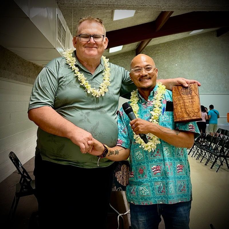 Two men are standing next to each other and one is holding a microphone.