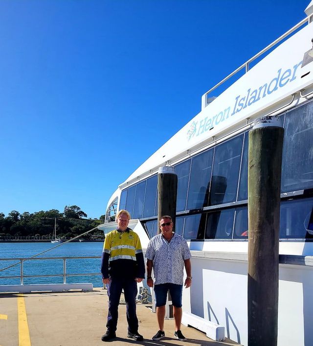 Two Men Are Standing In Front Of A Boat That Says ' Sydney Islands ' On It — Davey Service & Maintenance Qld In Clinton, QLD