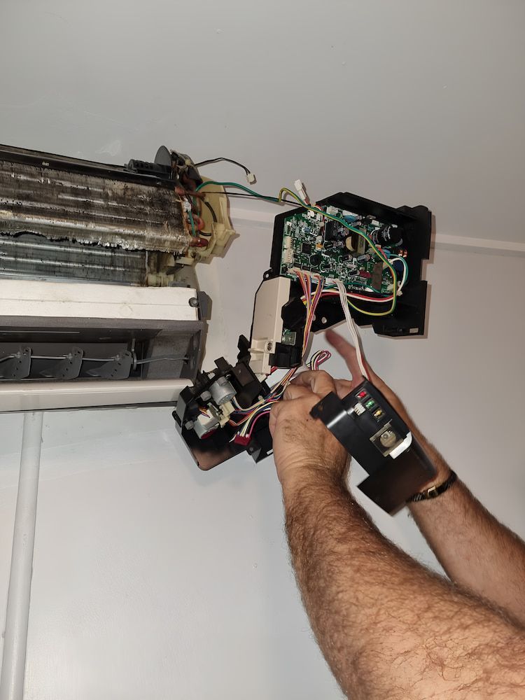 A Man Is Fixing An Air Conditioner With A Wrench — Davey Service & Maintenance Qld In Clinton, QLD