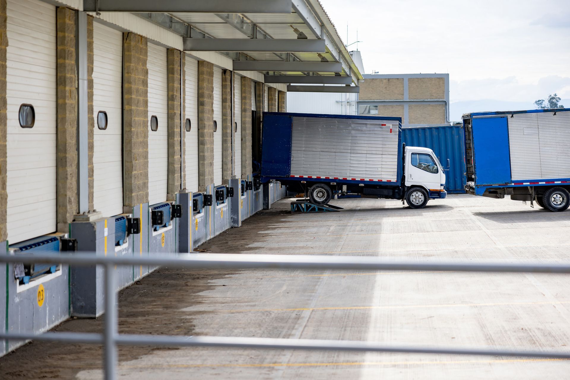 Trucks docked at loading docks, likely for freight, at a warehouse.
