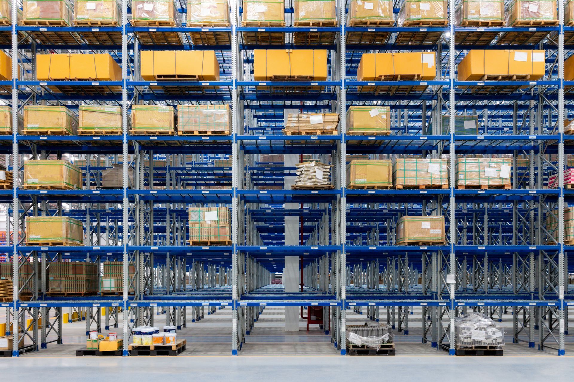Warehouse shelves stacked with boxes and pallets. Blue metal framework.