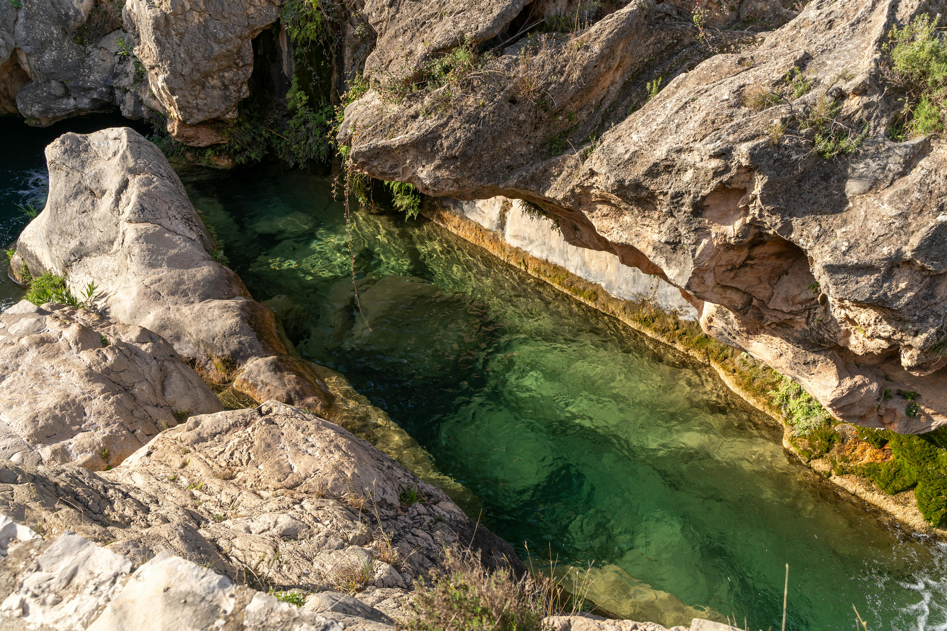 Clear, turquoise water flowing through a rocky canyon. Sunlight illuminates the water.